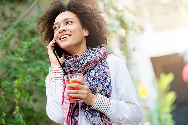 Beautiful girl with fruit cocktail using smartphone Coffee Break. Shallow DOF. Developed from RAW; retouched with special care and attention; Small amount of grain added for best final impression. 16 bit Adobe RGB color profile. pashmina stock pictures, royalty-free photos & images