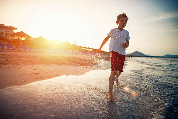 istock Little boy running on beach on sunset 547015610