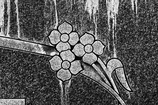 Flower engraving on old marble tombstone with white streaks and stains from weather and aging.