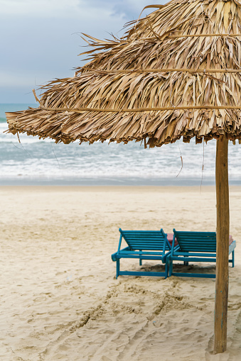 Palm shelter and sunbeds in the China Beach in Da Nang, Vietnam. It is also called Non Nuoc Beach. South China Sea on the background.