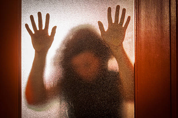istock Frightened Woman Behind Glass Door 547017194