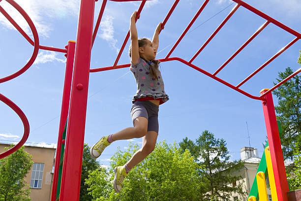 kleines mädchen spielt auf spielplatz, hängenspaziergang entlang affenbars - klettergerüst stock-fotos und bilder