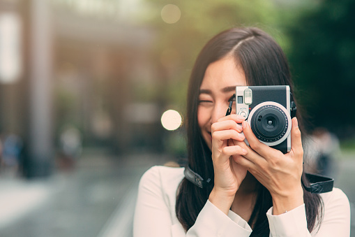 Portrait of a beautiful japanese woman taking a picture with a vinatage camera.