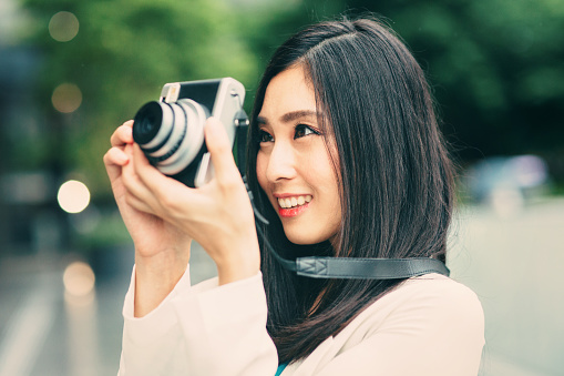 Portrait of a beautiful japanese woman taking a picture with a vinatage camera.