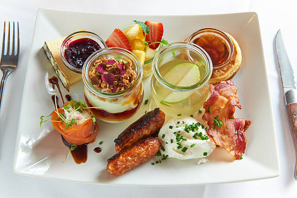 Breakfast plate with sausage, bacon, fruit, cheese and small pancakes