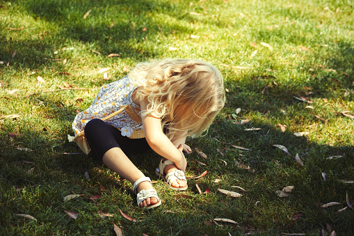 Little girl puts her sandals on.