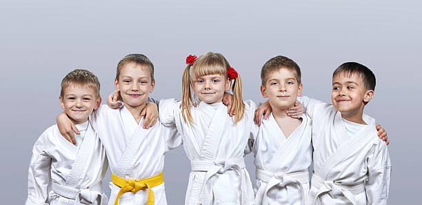 sobre un fondo gris pequeños atletas en karategi - karate child judo belt fotografías e imágenes de stock