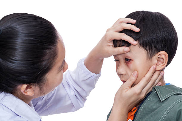 Pinkeye (conjunctivitis) infection on a boy, doctor check up eye stock photo