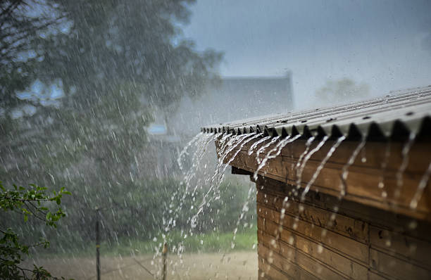 la lluvia fluye hacia abajo desde un techo hacia abajo - mojado fotografías e imágenes de stock