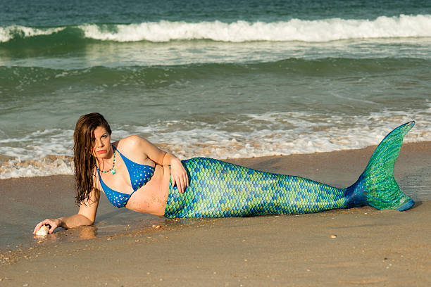 istock Mermaid with long dark hair and blue green tail 547034520