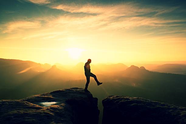 istock Man in black jumping between peaks. Dreamy daybreak 547034524