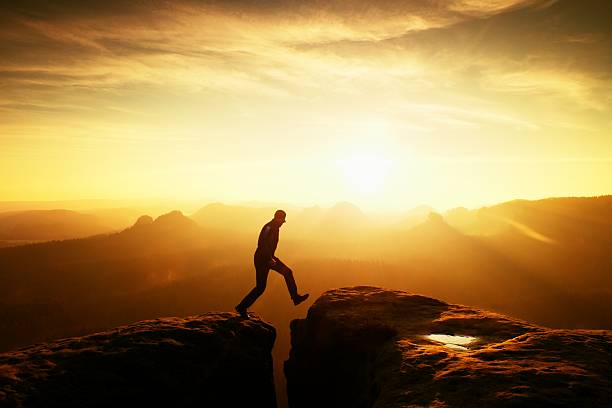 istock Jumping hiker in black triumph between rocky peaks. 547034682