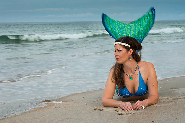 istock Mermaid with green tail lies in sand 547034946