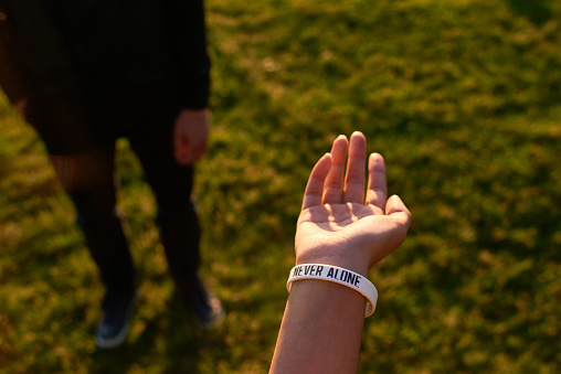 Close-up of female hand showing text on bracelet outdoors