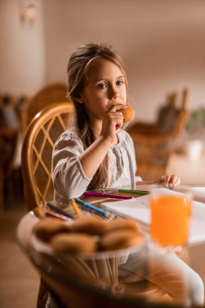 istock Cute little girl eating a cookie and thinking about something. 547038542