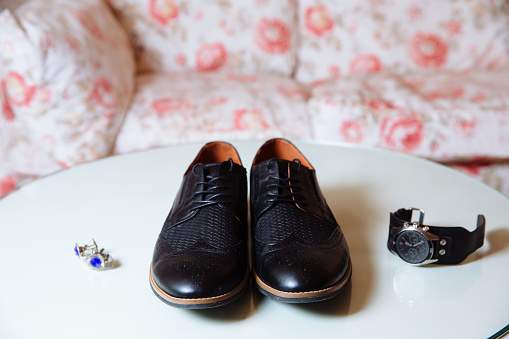 Gentlemans acessory. Shoes cuff links and waches on white table