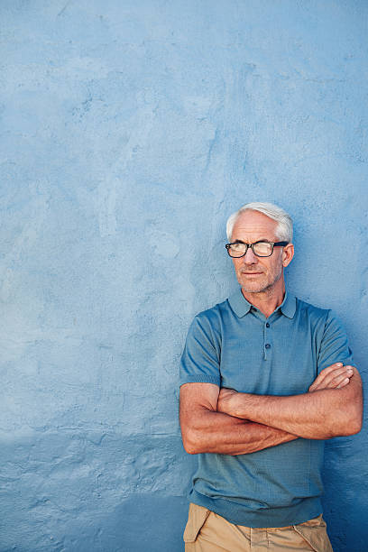 istock Mature man with glasses against a blue wall 547042560