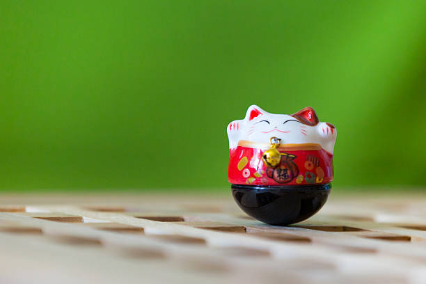 Beckoning lucky cat, maneki neko on green background with copy space