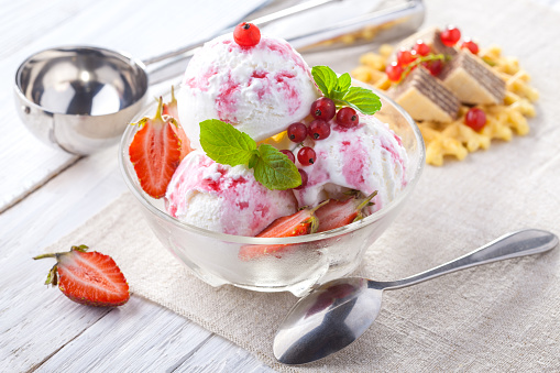 Ice Cream with Strawberry, Mint and waffles. Homemade Organic product. On the white wooden table.