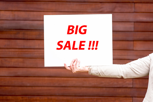 a picture of a woman holding a sale sign in his handa picture of a woman holding a sale sign in his handa picture of a woman holding a sale sign in his hand
