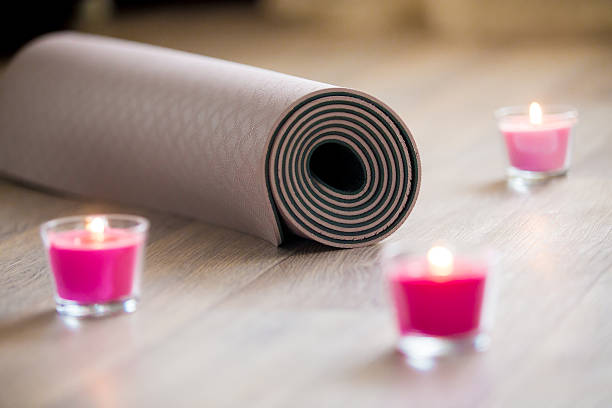 istock Folded brown yoga, pilates mat on floor with lighted rose 547049340