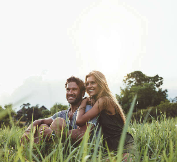 istock Loving couple sitting on grass field 547049356