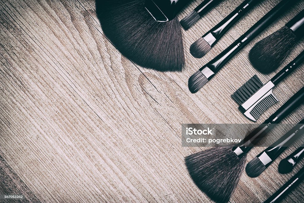 Beauty background with various makeup brushes Set of various makeup brushes: for applying powder, eyeshadow, eyebrow brushes, fan brushes and others. Professional tools of makeup artist on shabby wooden surface. Copy space. Retro style processing Make-Up Artist Stock Photo