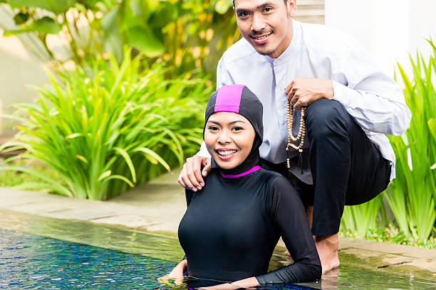 muslim woman in pool greeting her husband - 回教泳裝 圖片 個照片及圖片檔