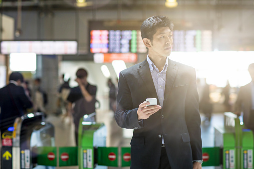 Businessman looking for directions on the mobile phone at the station in Tokyo.