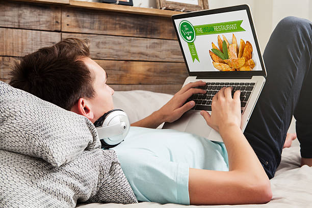 istock Man visiting a vegan restaurant website, lying at home. 547055398