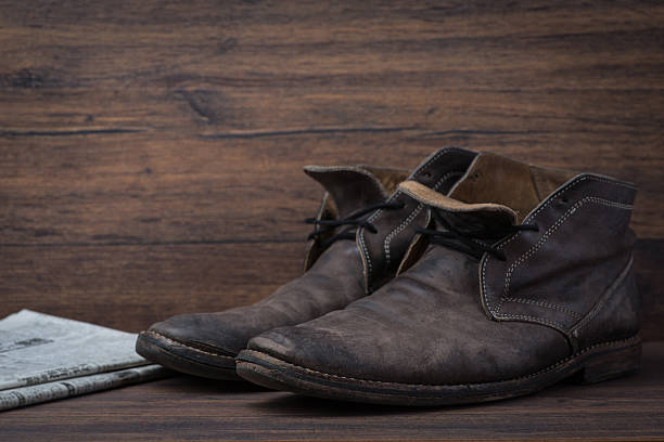 istock Old worn out brown leather shoes with newspaper 547056660