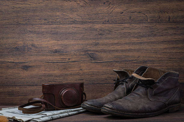 istock Old worn out brown leather shoes with camera and newspaper 547056716