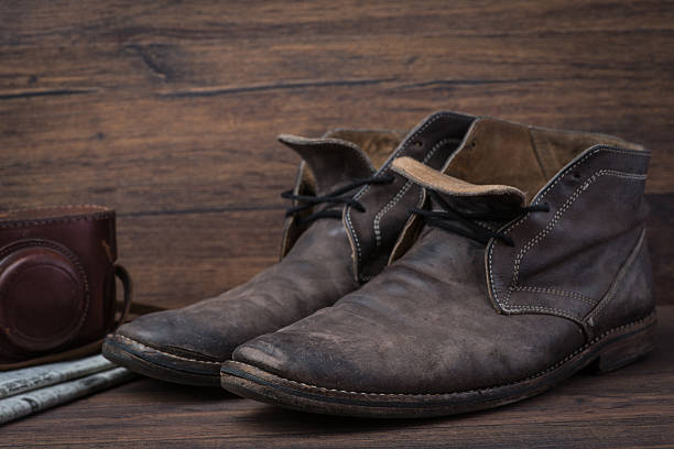 istock Old worn out brown leather shoes with camera and newspaper 547056800