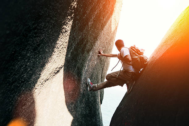 Brave man sitting in canyon with backpack (intentional sun glare)