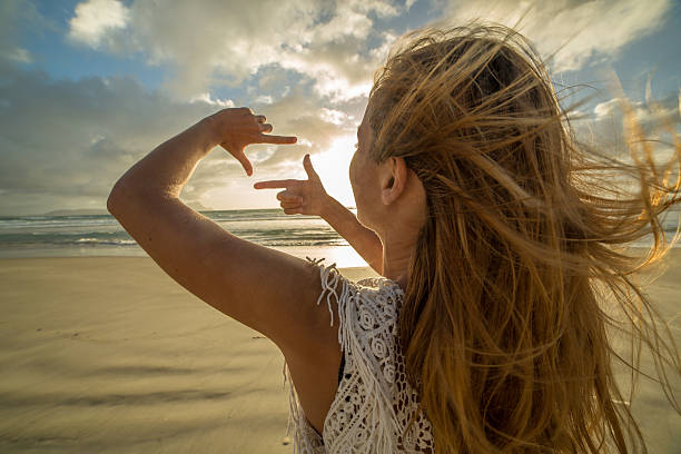 istock Young woman makes natural frame with fingers on sunset 547124504