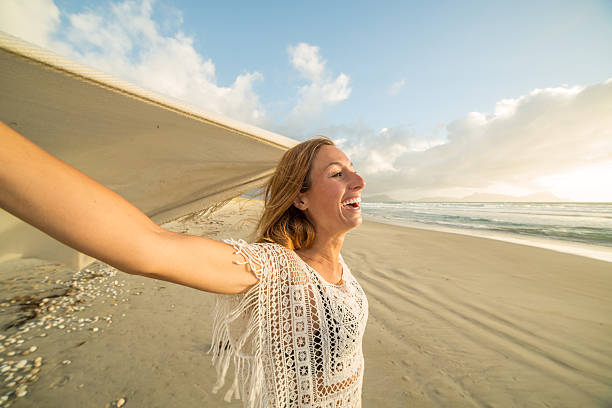 istock Woman walks on beach with blanket in the wind 547125180