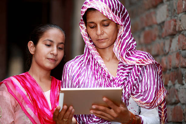 mère et fille tenant une tablette numérique - global village photos et images de collection