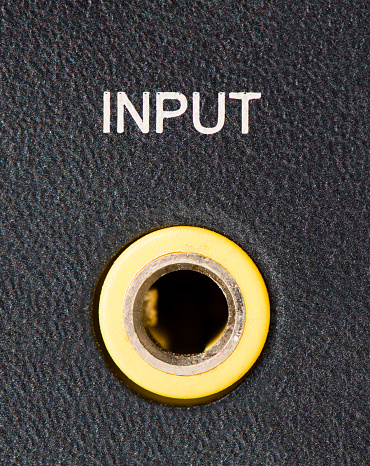 Closeup of a yellow headphone/auxiliary port on the back of a computer speaker.