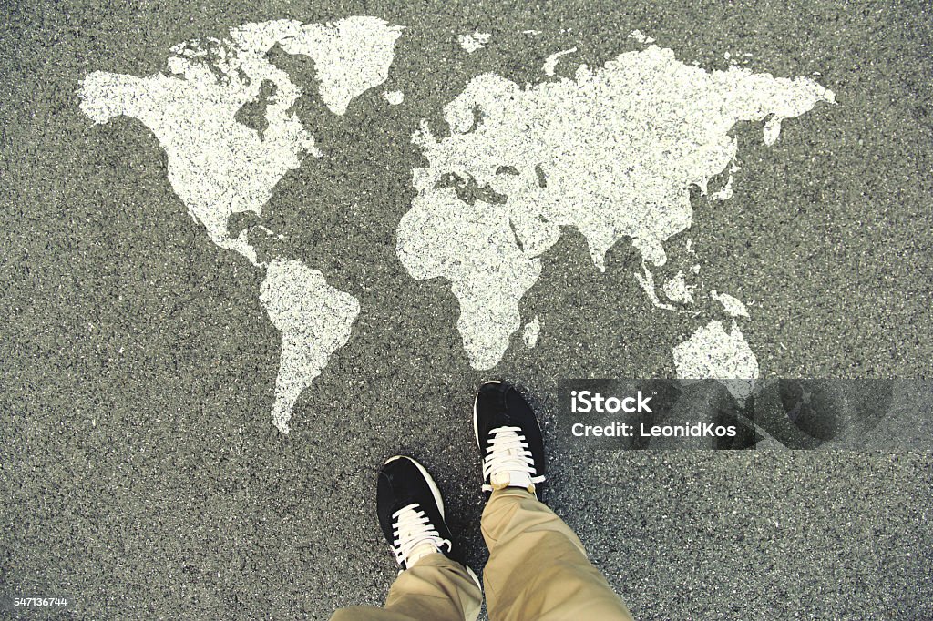 World map on an asphalt road World map on an asphalt road. Top view of the legs and shoes. POV World Map Stock Photo