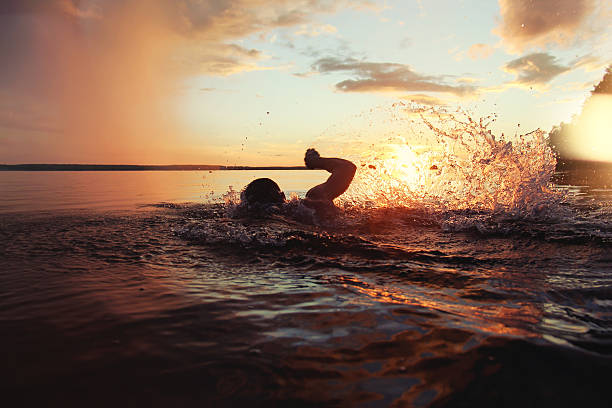 istock Athletic man is trained to swim in lake at sunset 547139920