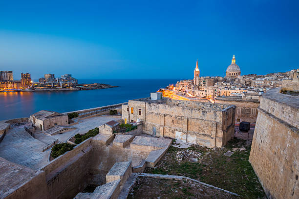 Valletta, Malta - Ancient walls of Valletta Valletta, Malta - Ancient walls of Valletta and St.Paul's Anglican Cathedral and houses of Sliema at blue hour st paul cathedral la valletta malta island stock pictures, royalty-free photos & images