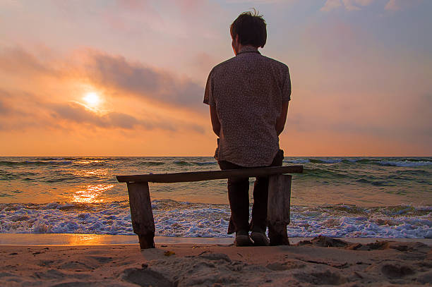 istock Lonely man sits on a bench on the beach 547142424