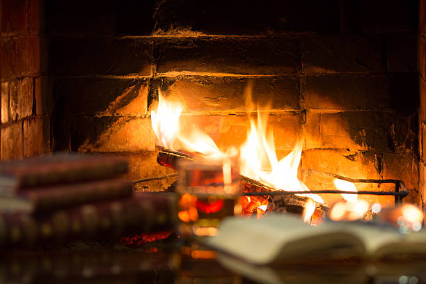 istock Glass alcoholic drink wine antique books in front warm fireplace. 547143000