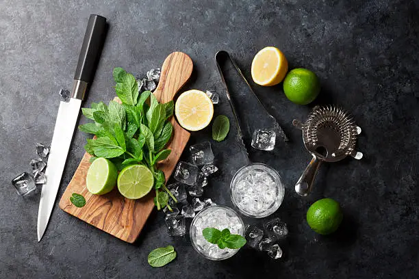 Mojito cocktail making. Mint, lime, ice ingredients and bar utensils. Top view