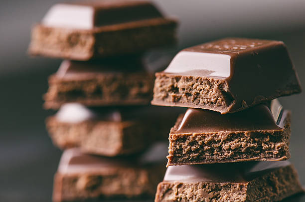 due edifici di cioccolato su sfondo scuro. energia e zucchero. - brown chocolate candy bar close up foto e immagini stock