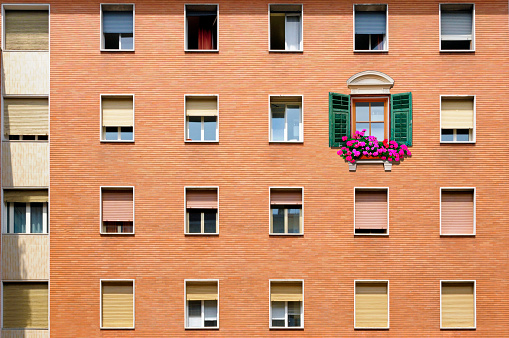 A baroque window with flowers on a modern, regular building facade
