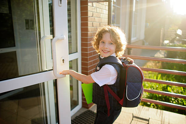 istock Little curly schoolboy opens a school door 547144328