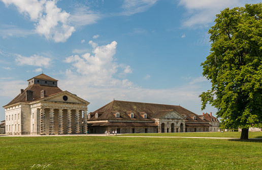 Guise, France - August 5, 2022: The rear of the Social Palace of the Familistère, a phalanstery-type housing complex built by Godin in the 1860s, and its large domed tower overlook a tree-filled park.