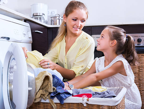 ama de casa y chica haciendo lavandería - stereotypical housewife little girls family domestic kitchen fotografías e imágenes de stock