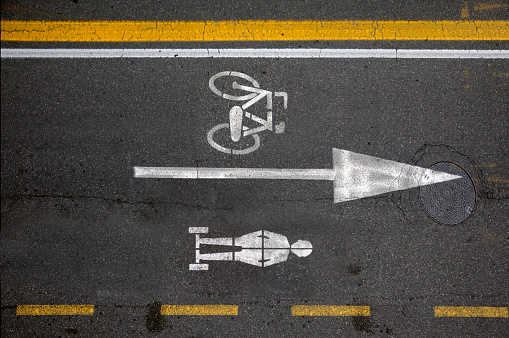 Street signs on the asphalt, lane for bicycles and lane for balance board.